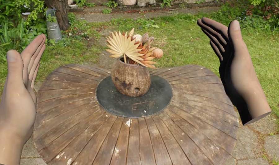 A screen shot from a virtual reality scene shows two hands on either side of a table with a coconut centerpiece.
