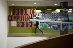 A person walks in front of a mural that also says School of Computer Science.
