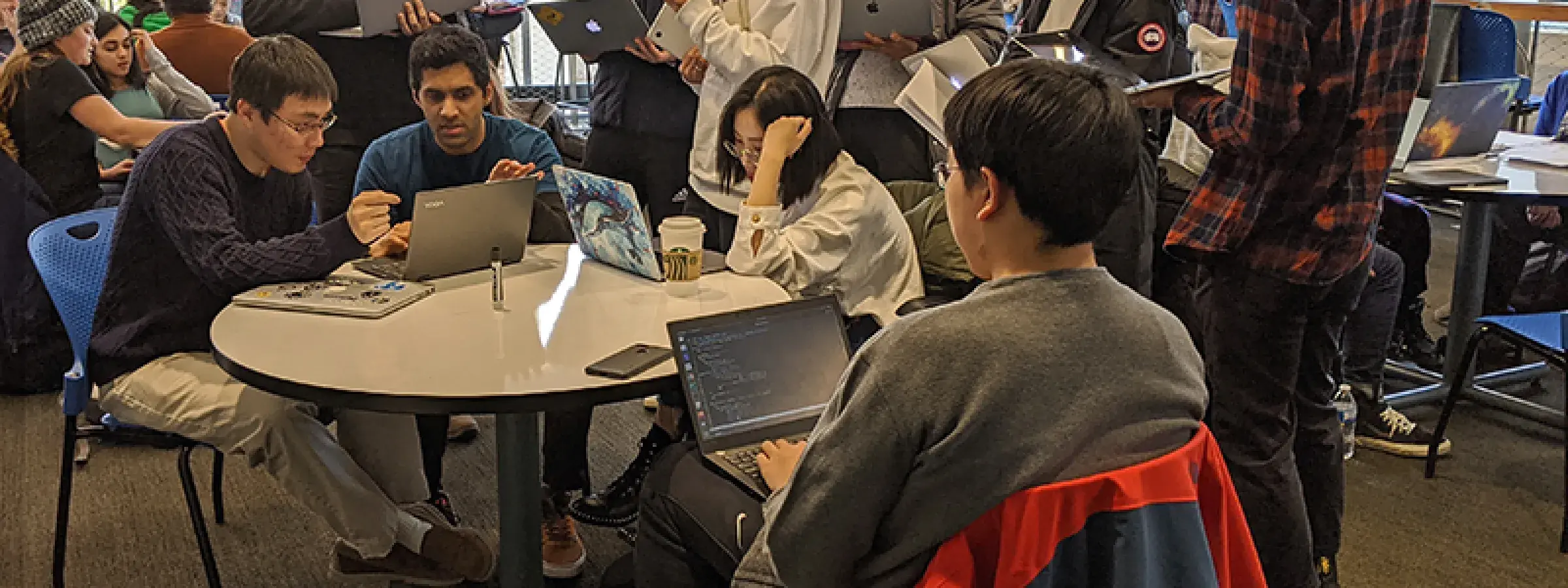 group of students with laptops working at a table